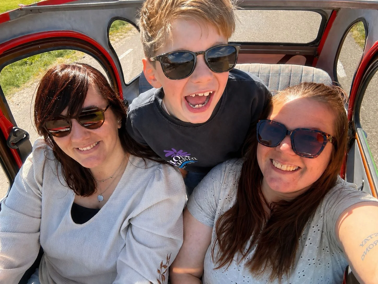 Three happy passengers in a 2CV with open roof
